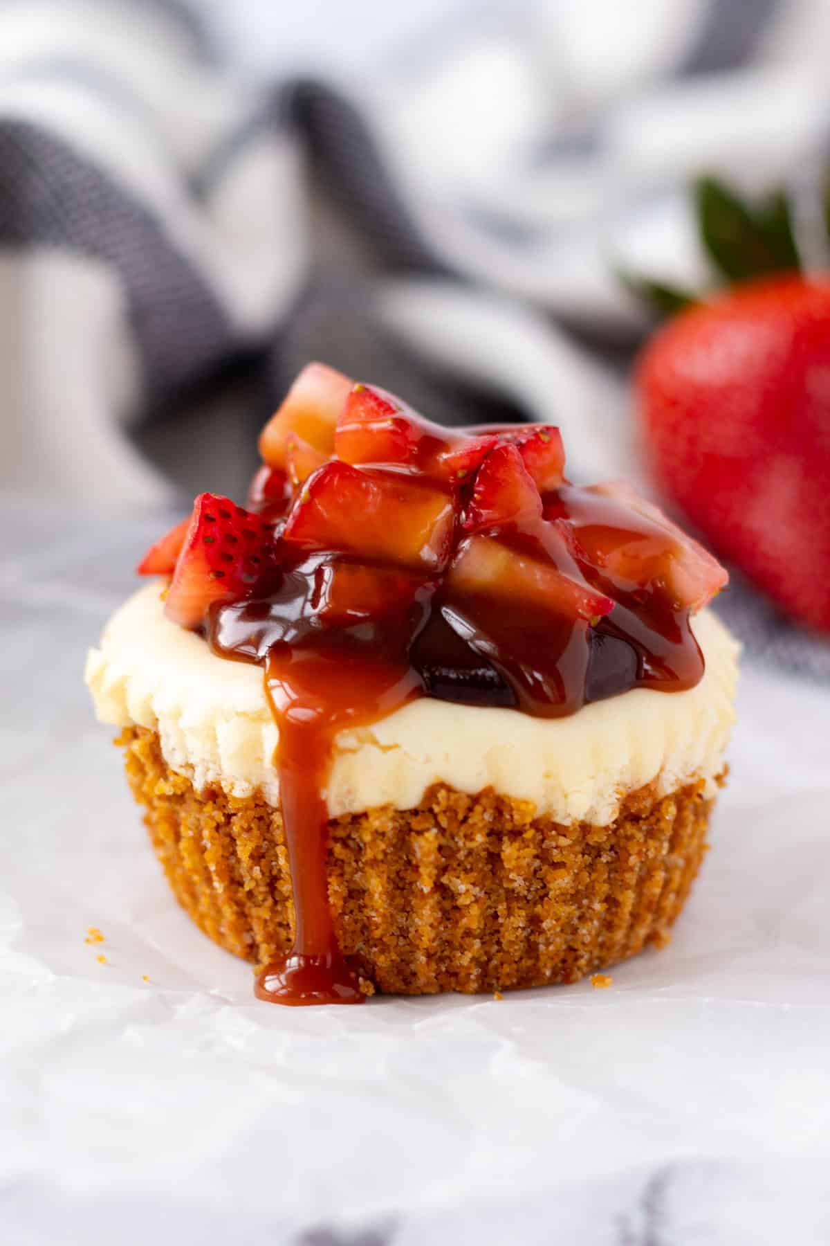 One single strawberry nutella cheesecake with caramel sauce dripping off of the side.