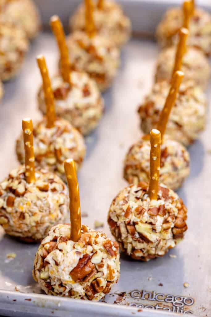 Adding a pretzel stick to the tops of the cheese balls.