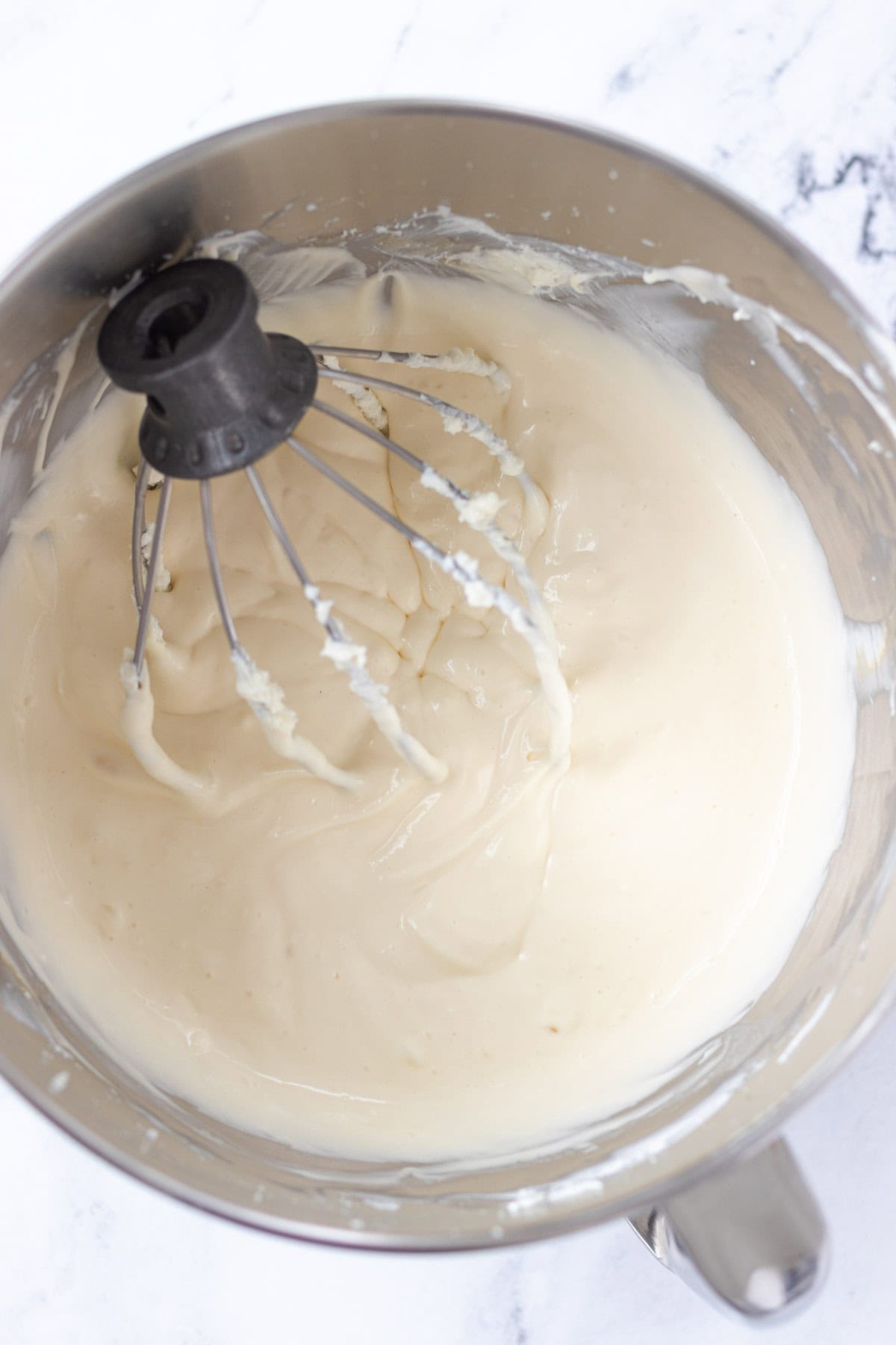 Mixing the cheesecake filling in the bowl of a stand mixer.