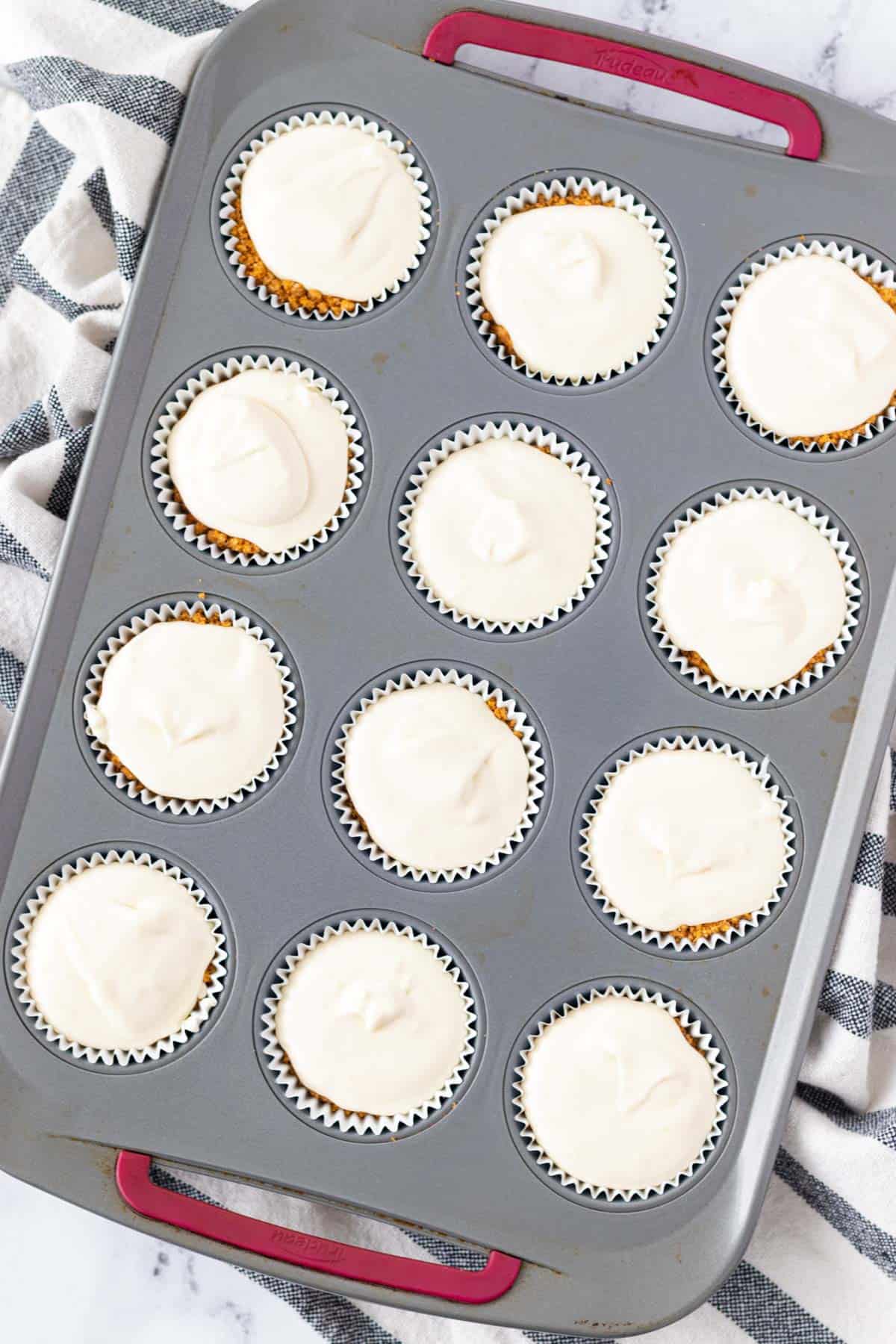 Filling the liners with cheesecake filling.