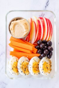 Lunchable with apple slices, apple dip, carrot sticks, chocolate acai berries, and hard boiled eggs.