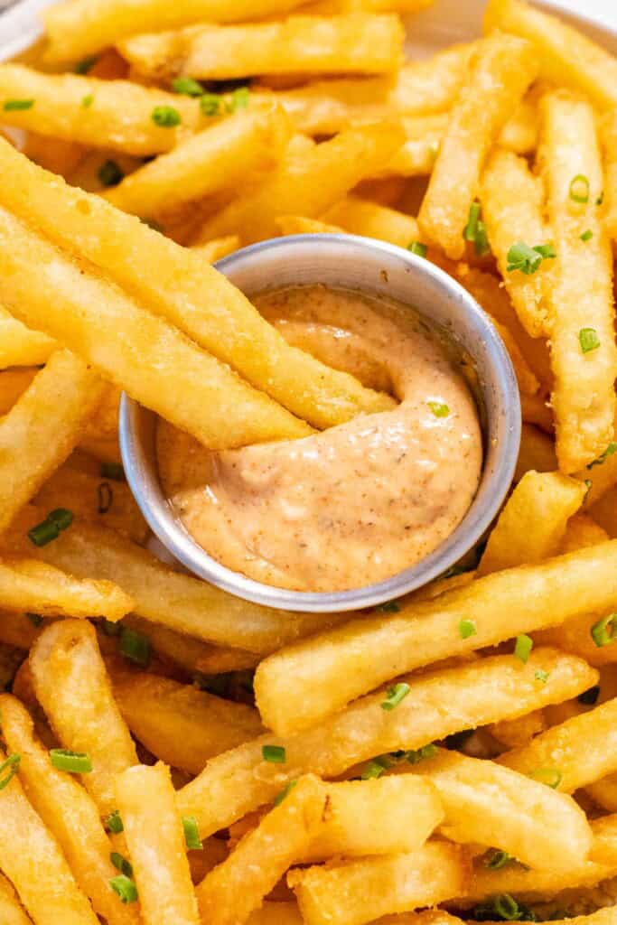Dipping french fries into sriracha aioli.