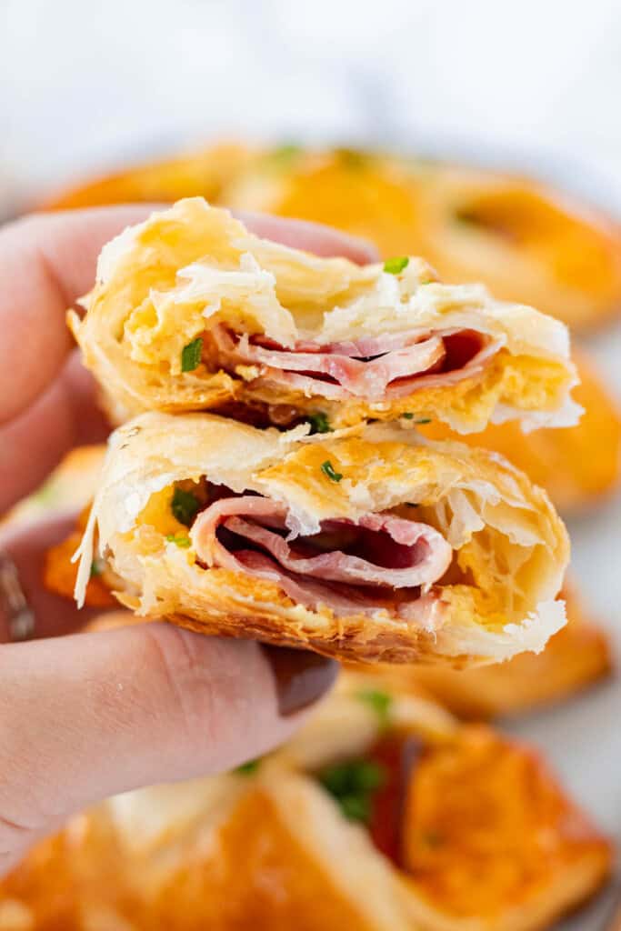 A croissant ripped in half showing the inside stuffed with ham and cheese.