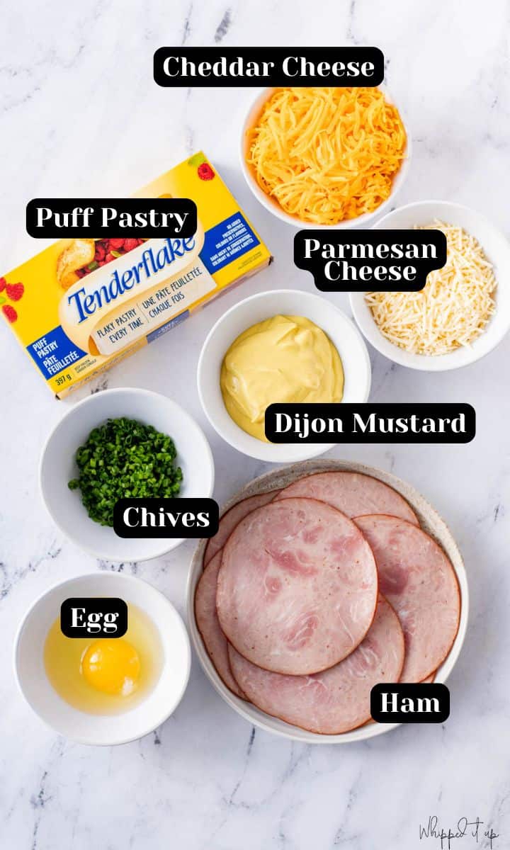 Ingredients to make ham & cheese croissants include cheddar cheese, puff pastry, Parmesan cheese, dijon mustard, chives, egg, and ham.