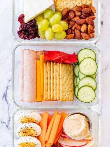 Three adult lunchable options in a row. Ham and cheese, brie and almond and, egg and apple.