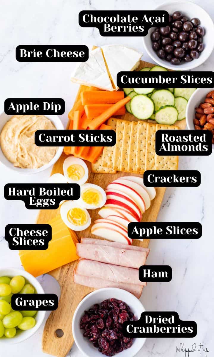 Ingredients to make all 3 lunchables include chocolate acai berries, brie cheese, cucumber slices, apple dip, carrot sticks, roasted almonds, crackers, hard boiled eggs, apple slices, ham, cheese slices, grapes, and dried cranberries.