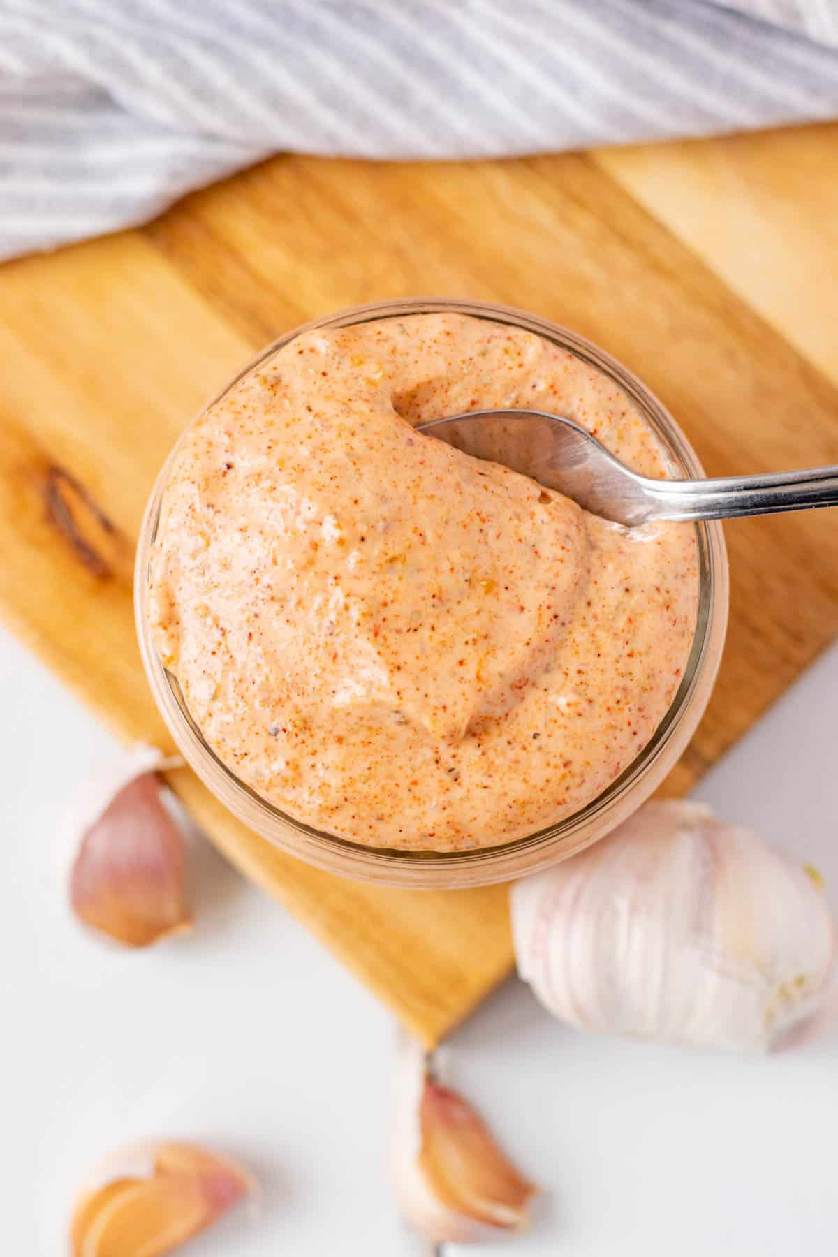 A jar of sriracha aioli with a spoon in it.