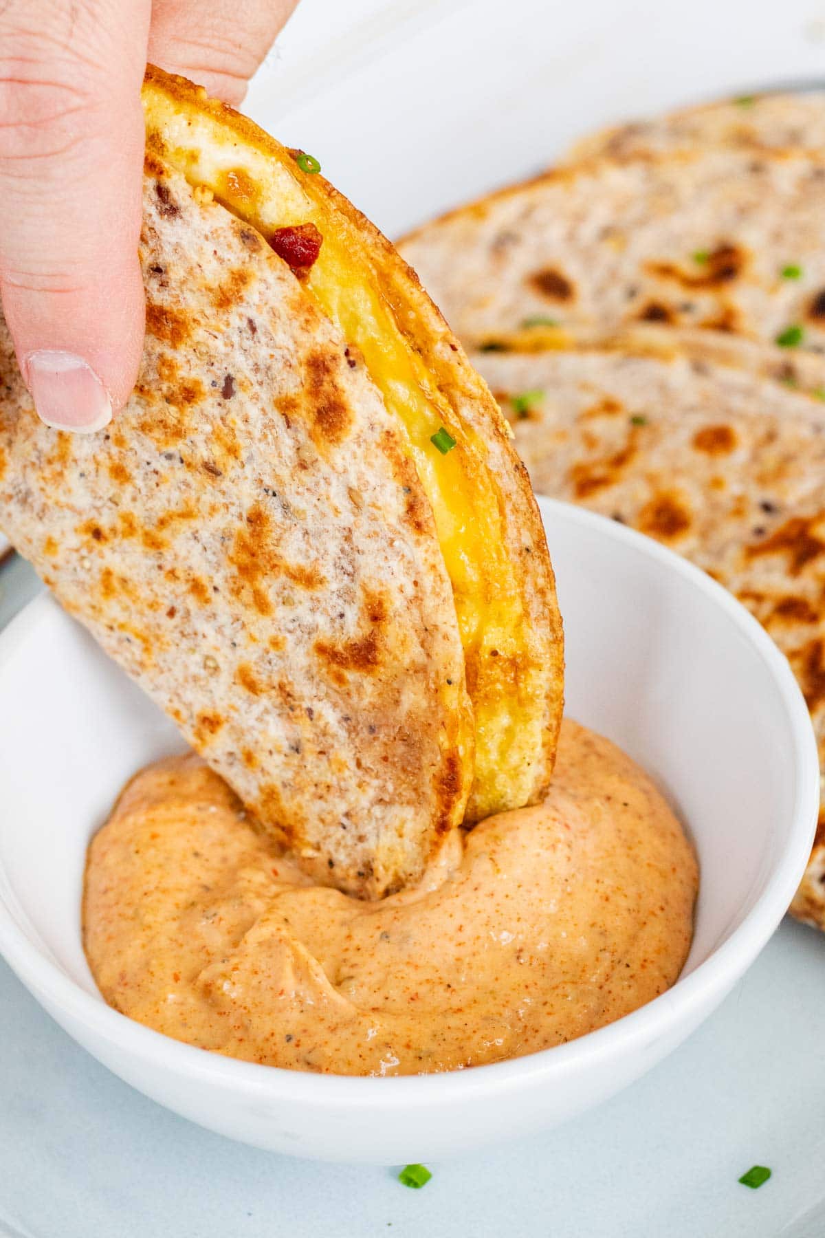 Dipping a breakfast taco in a bowl of sriracha aioli sauce.