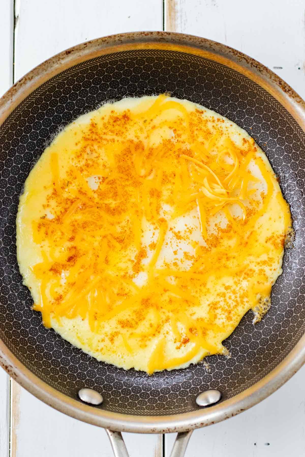 Adding the whisked egg, cheese, and spices to the frying pan.
