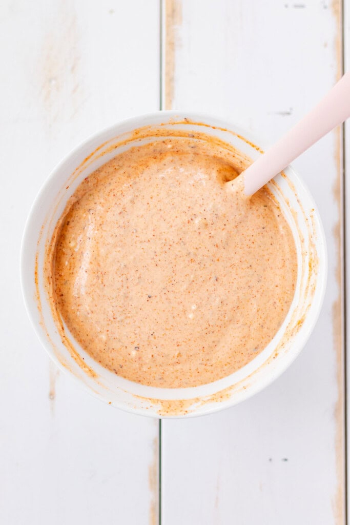 Stirring the sriracha aioli in a white bowl.
