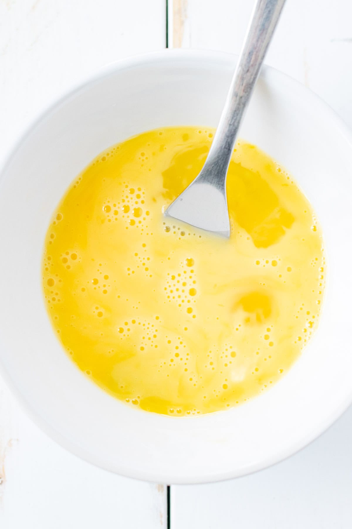 Whisking one egg in a bowl with a fork.