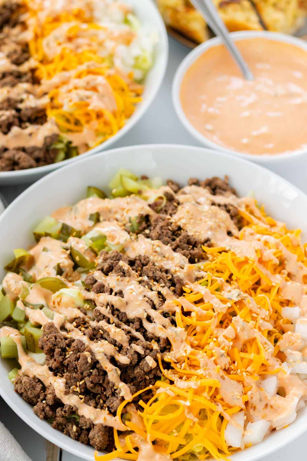 A large big mac salad in a white bowl with all the toppings.