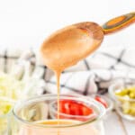 Big mac sauce dripping off of a wooden serving spoon.