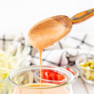 Big mac sauce dripping off of a wooden serving spoon.