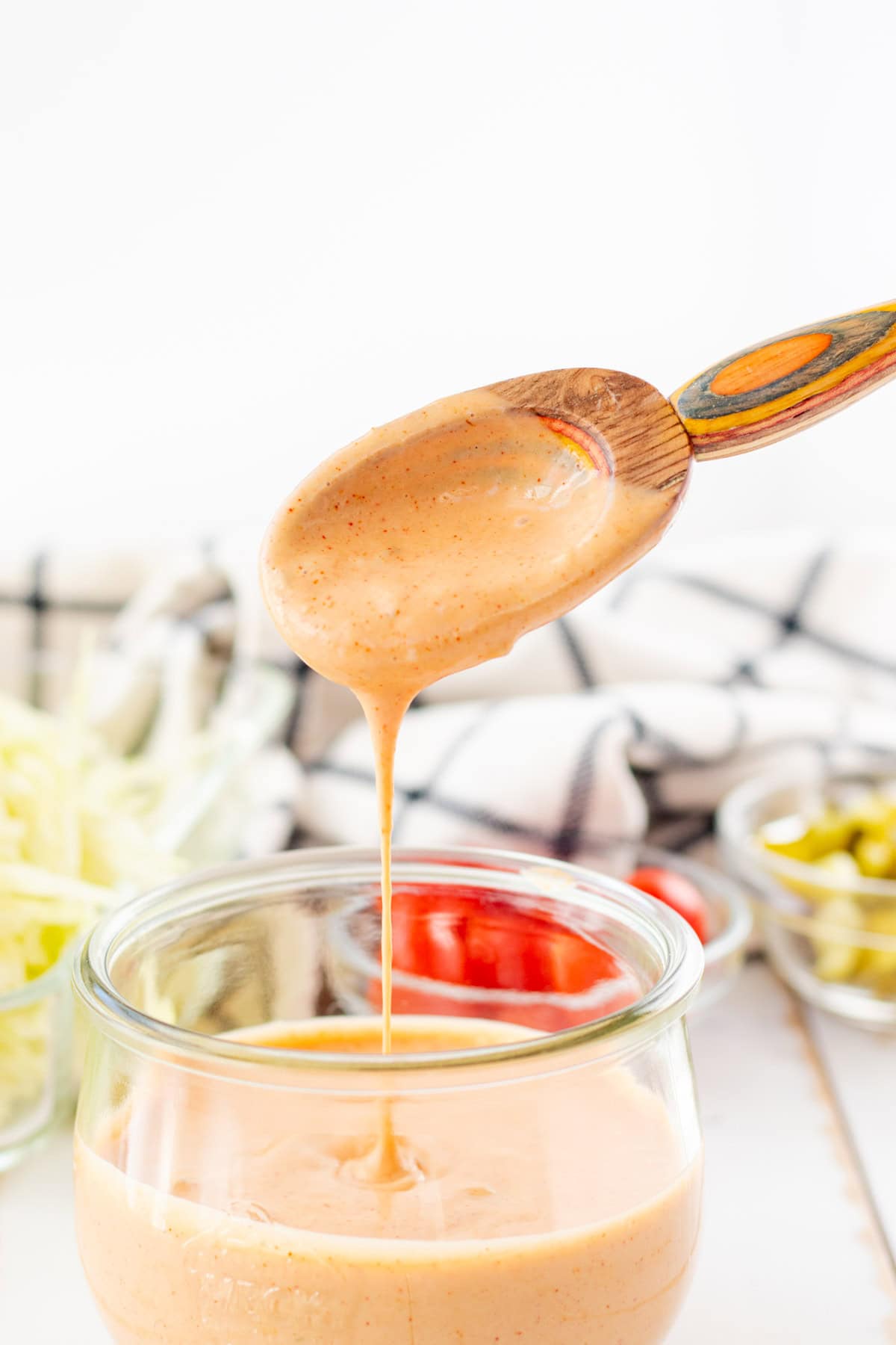 Big mac sauce dripping off of a wooden serving spoon.