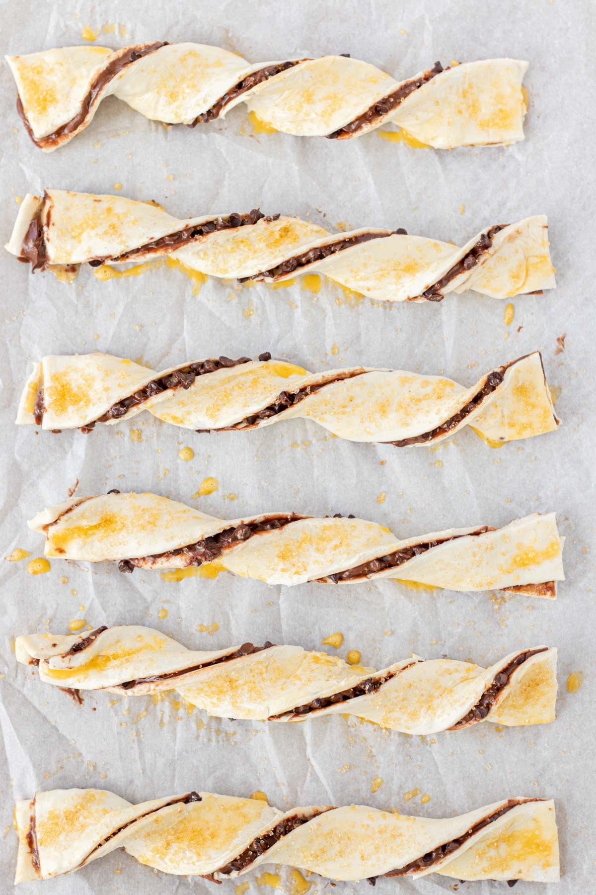 Brushing the chocolate twists with egg wash and sprinkling on turbinado sugar.