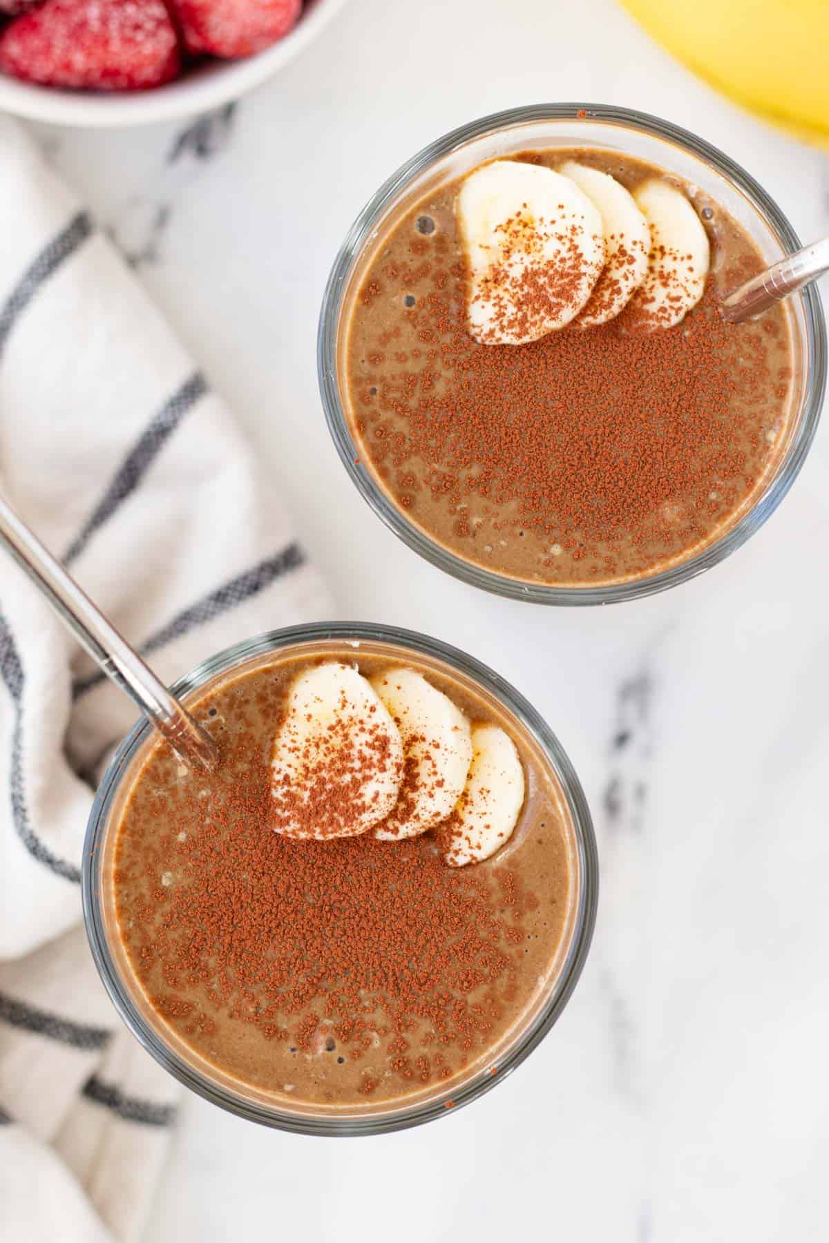 Two glasses of chocolate smoothies with cocoa sprinkle.