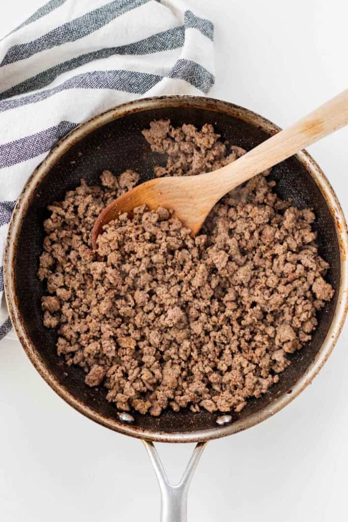 Cooking the ground beef until fully browned with the spices and Worcestershire sauce.