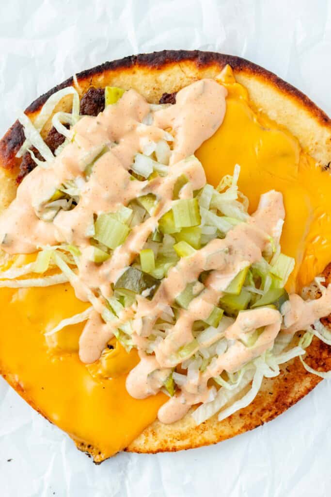 Filling the tacos with shredded lettuce, pickles, onions and big mac sauce.