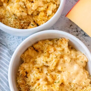 Two white serving bowls filled with creamy gouda mac and cheese.
