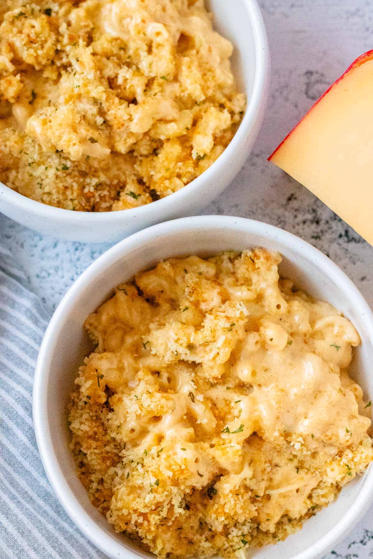 Two white serving bowls filled with creamy gouda mac and cheese.
