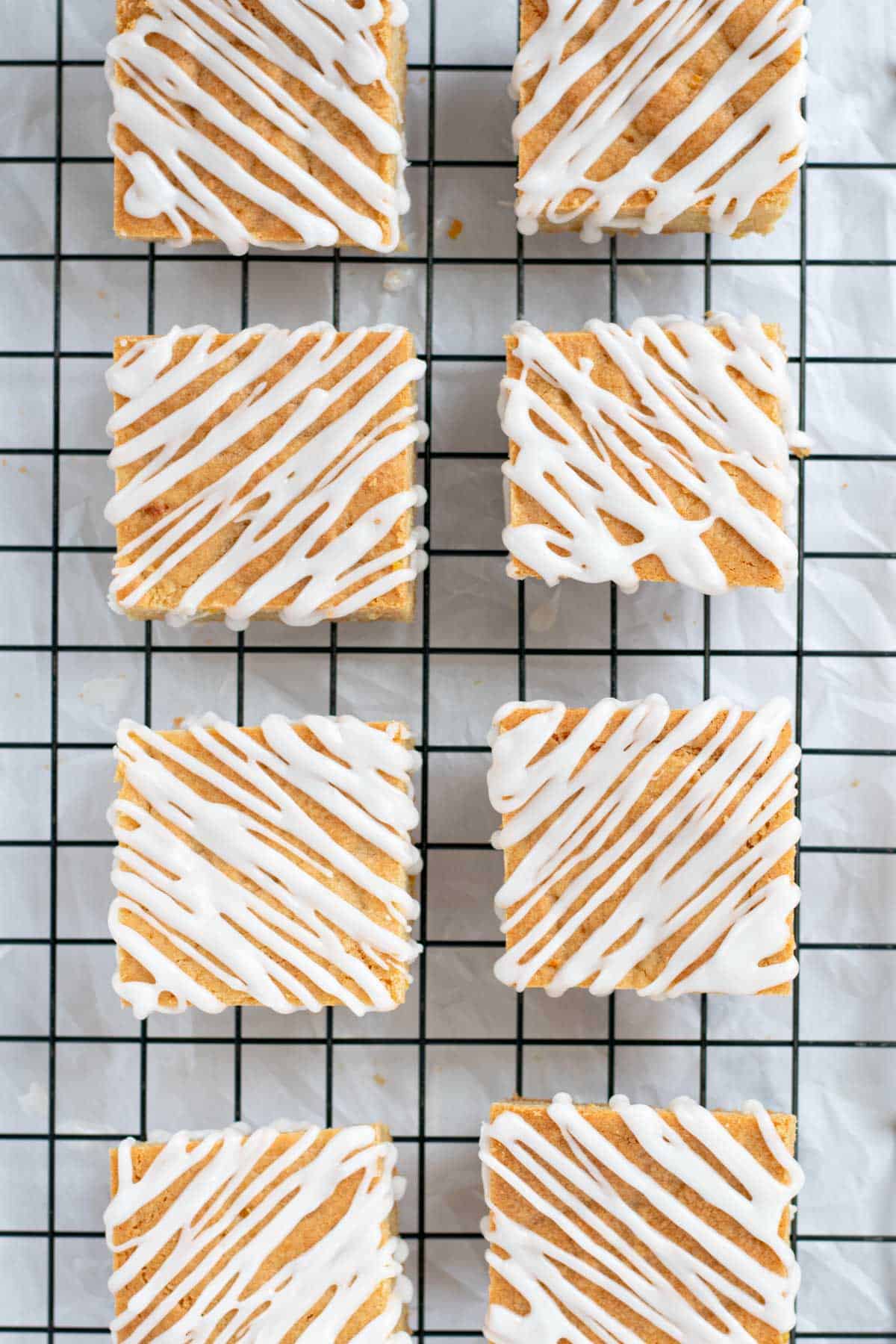 Lemon blondies on a wire rack being drizzled with glaze.
