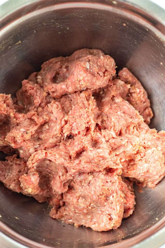 Mixing the ground beef with cumin, an egg, panko breadcrumbs, salt and pepper.
