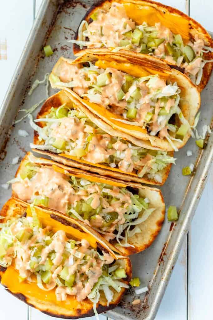 A large serving tray with five big mac tacos lined up.