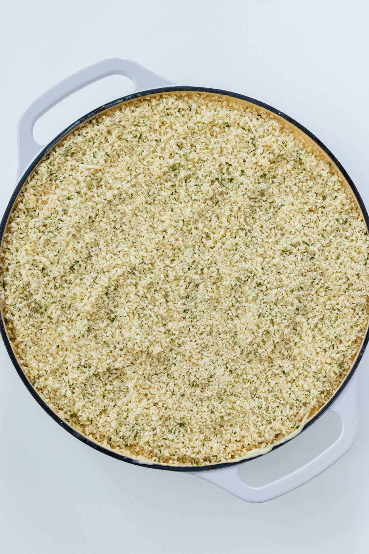 Topping the mac and cheese with Parmesan and the prepared panko topping.