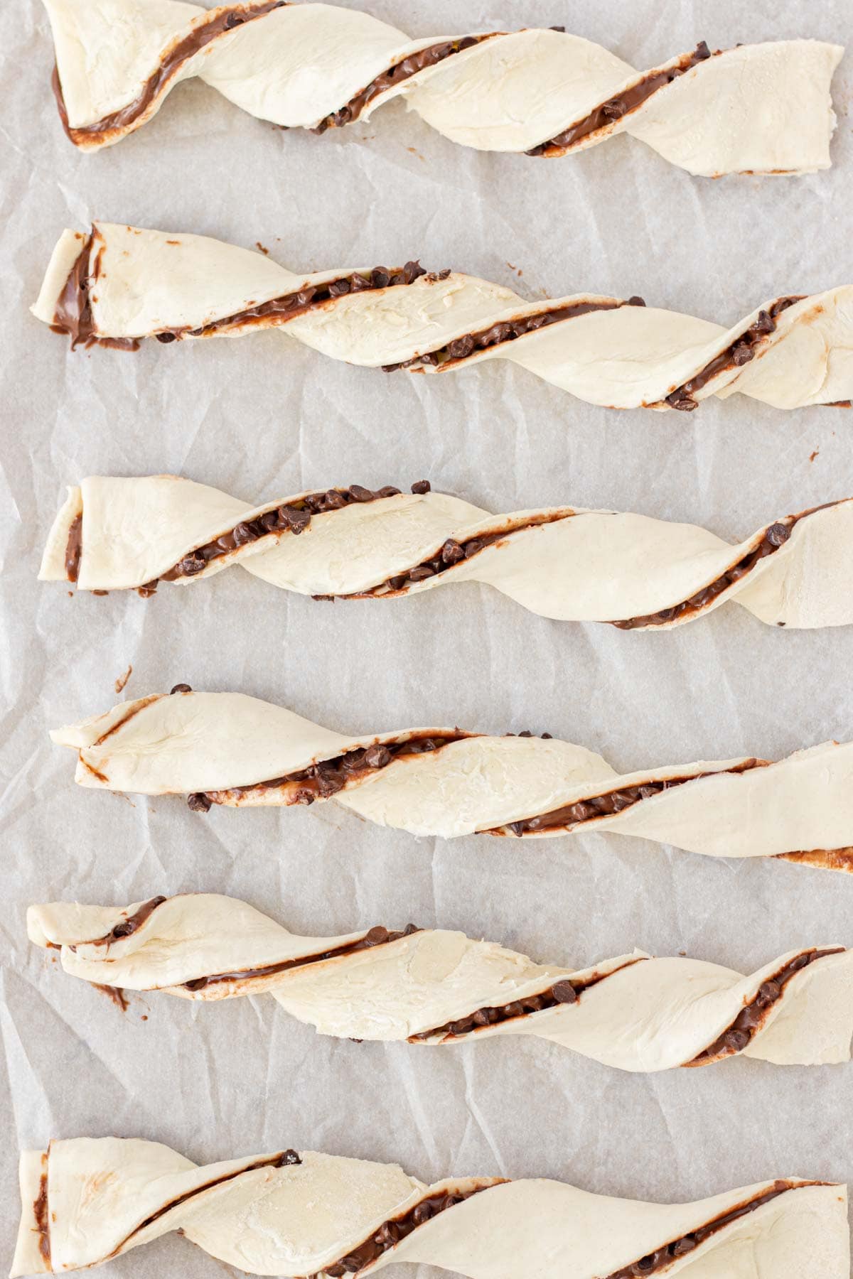 Twisting the chocolate pastries and placing them on a parchment lined baking sheet.