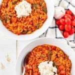 Two large bowls filled with lasagna soup and topped with a dollop of spiced ricotta topping.