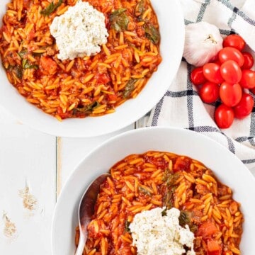 Two large bowls filled with lasagna soup and topped with a dollop of spiced ricotta topping.