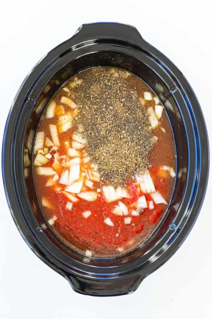Adding all of the ingredients into the slow cooker after browning the beef.