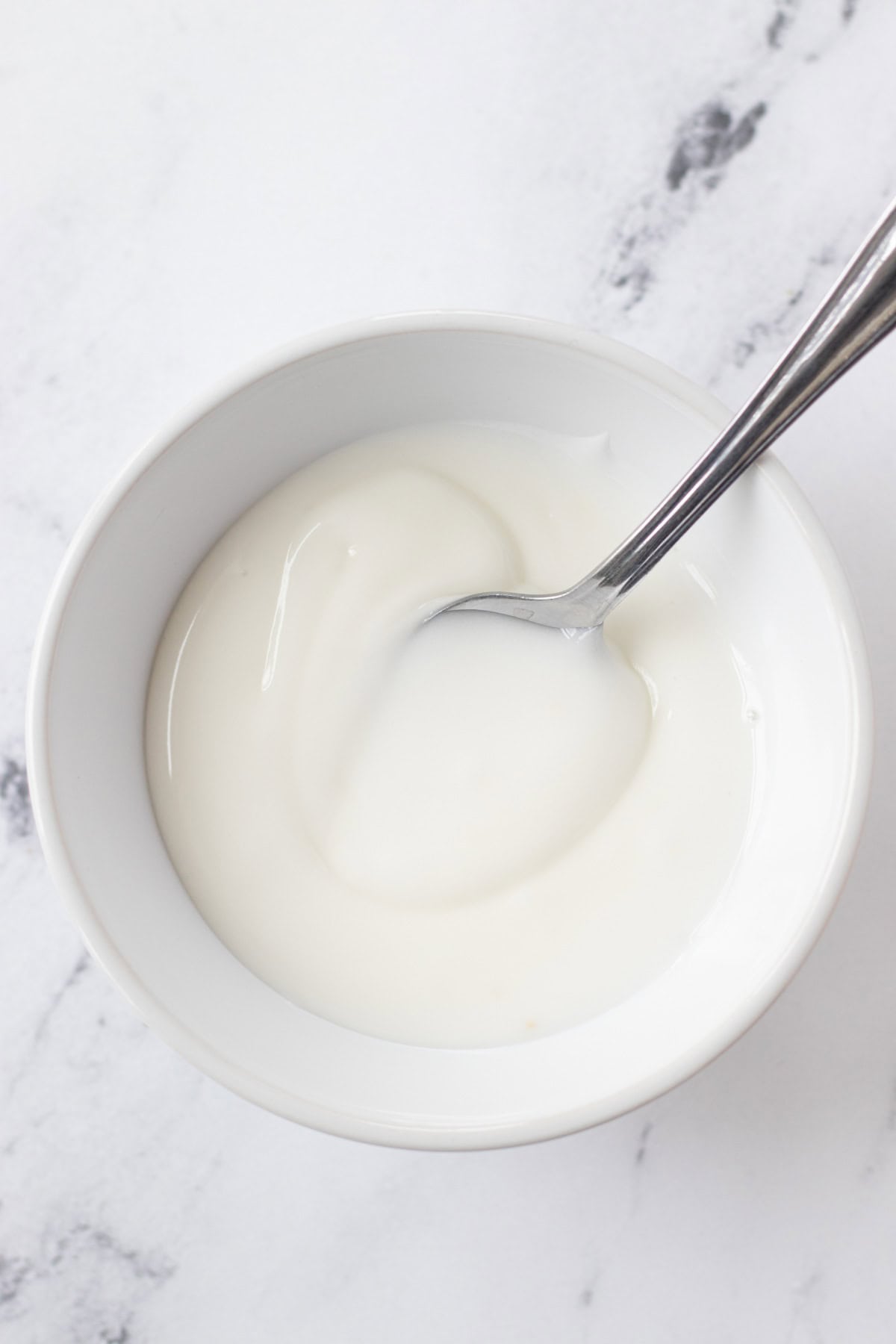 Stirring the powdered sugar and lemon juice together to make a glaze.
