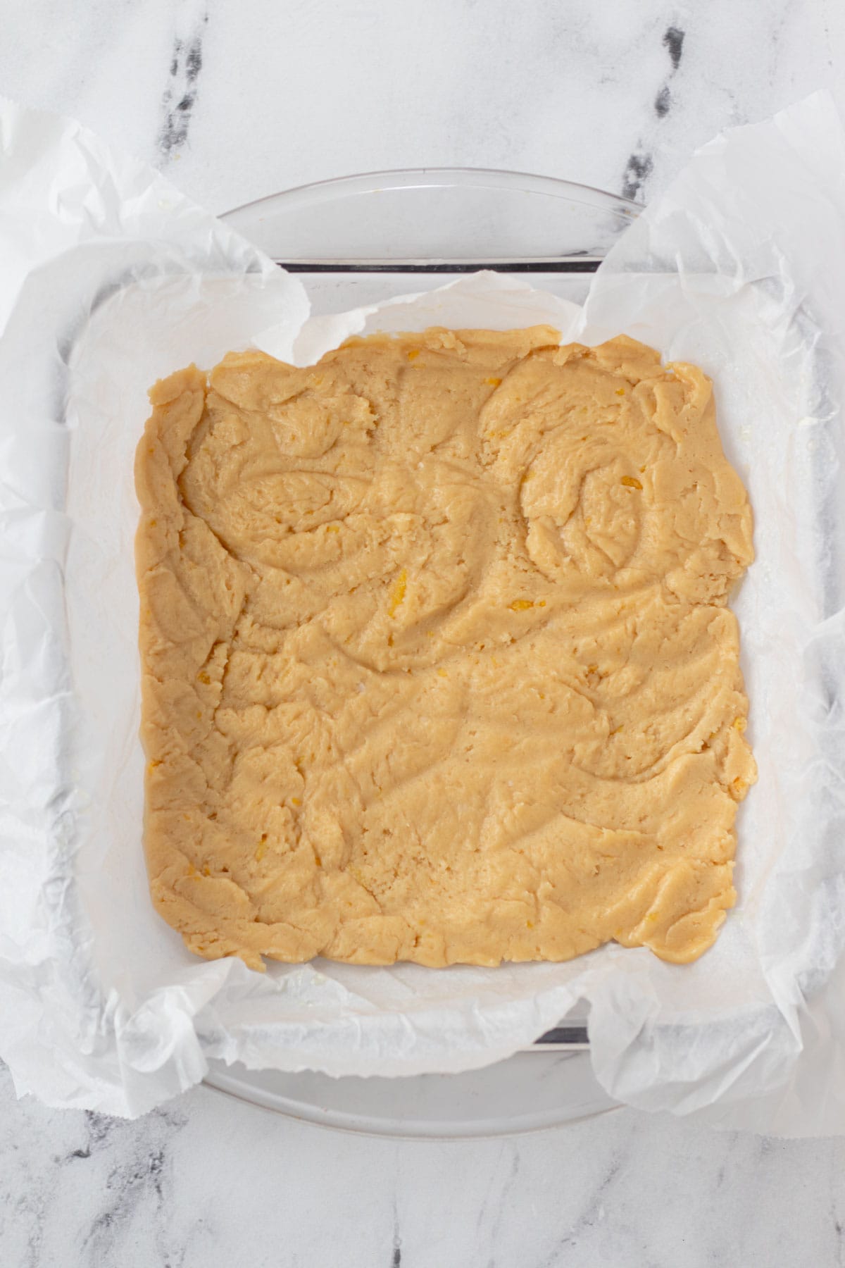 Pressing the lemon blondie batter into a lined baking pan.