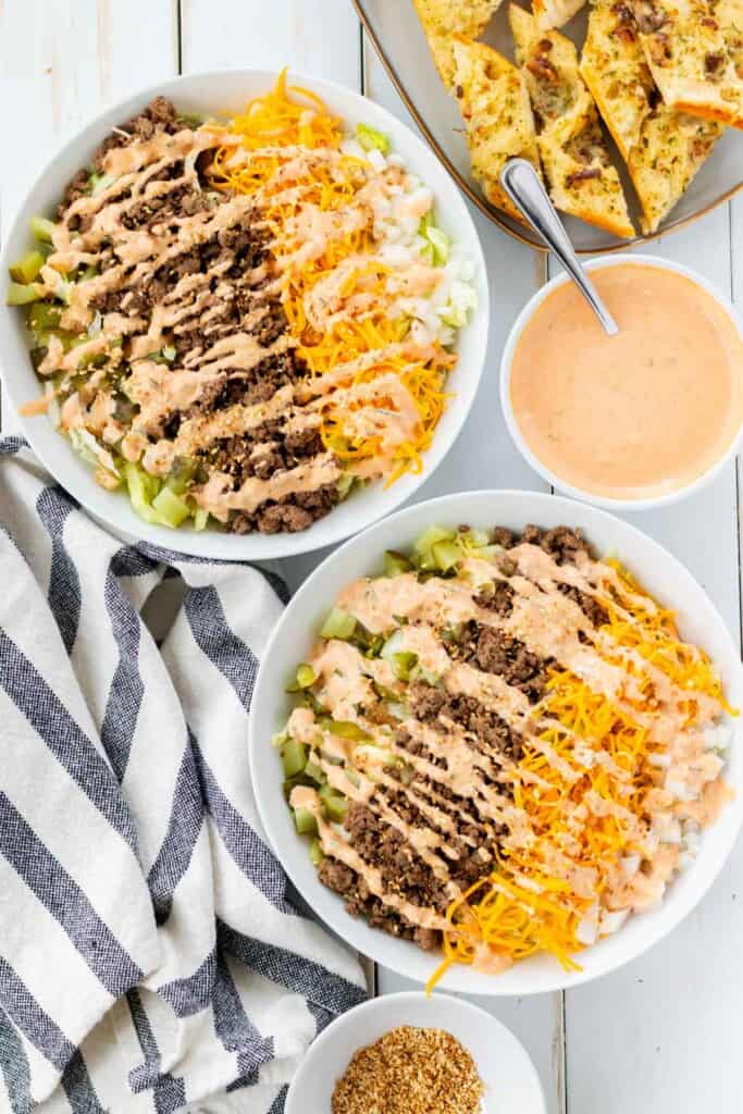 Topping the big mac salads with toasted sesame seeds and big mac sauce.