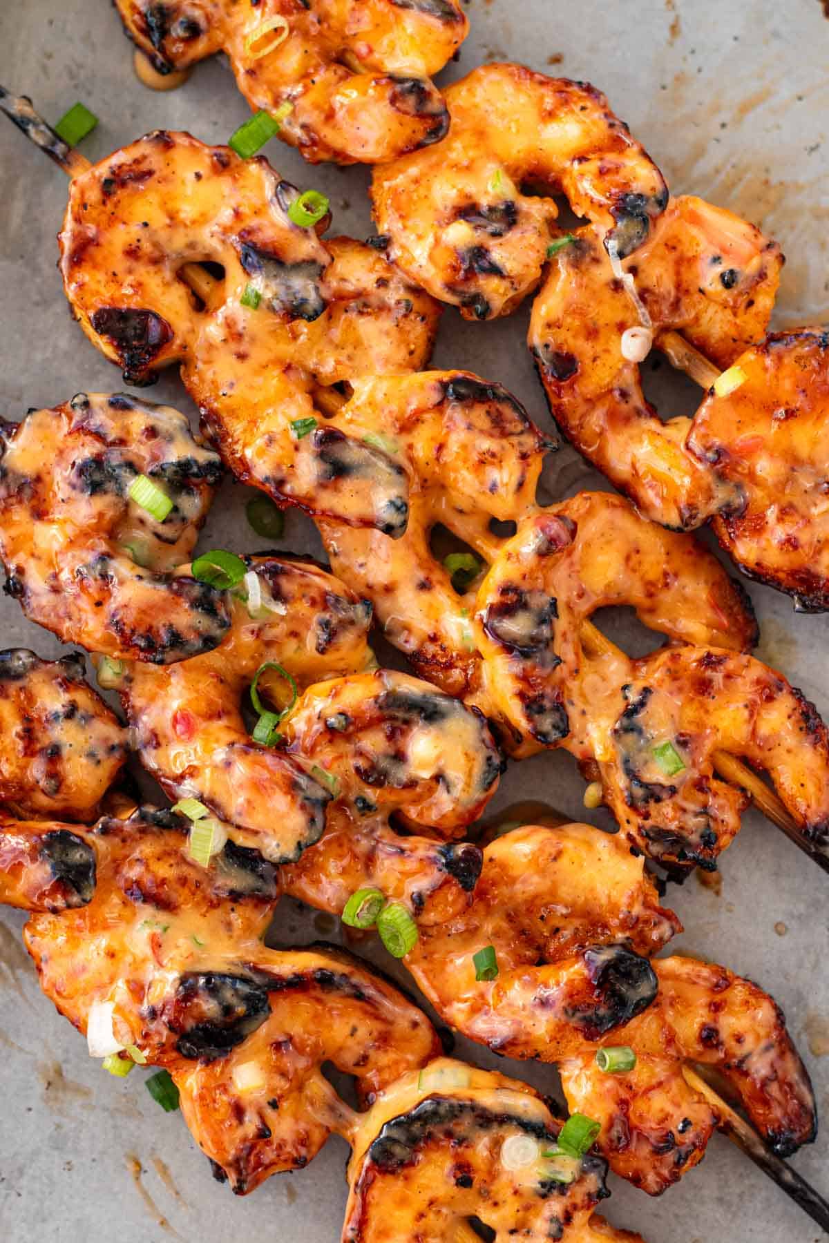 Brushing grilled shrimp with bang bang sauce.