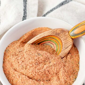 Cajun seasoning blend in a white bowl with a wooden spice spoon.