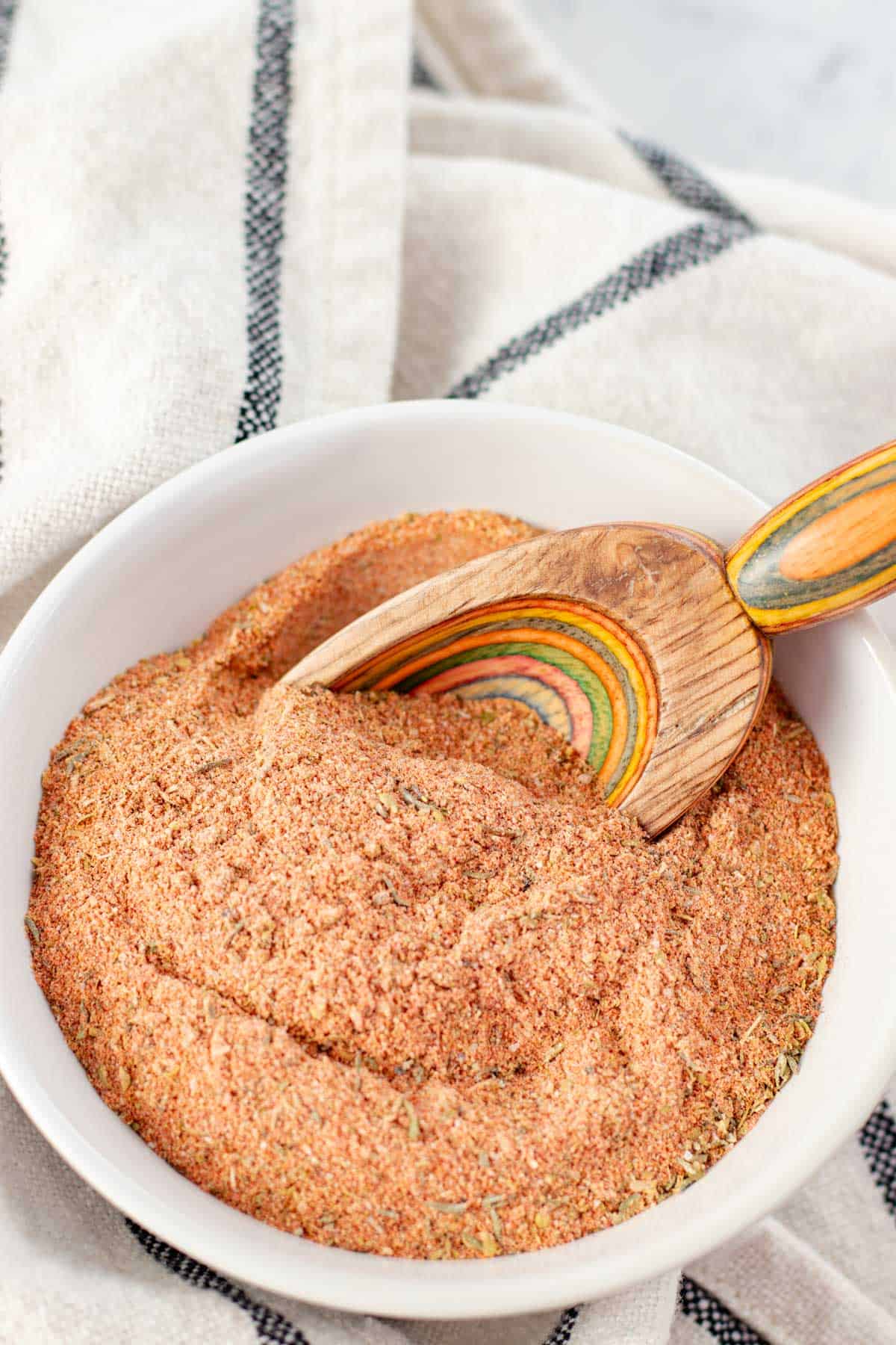 Cajun seasoning blend in a white bowl with a wooden spice spoon.