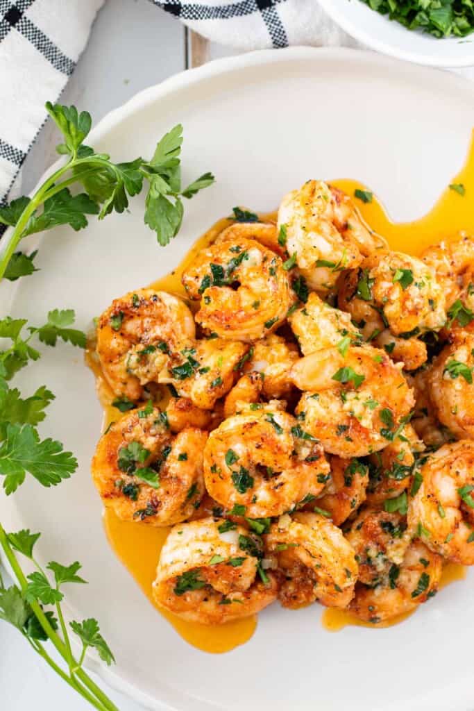A white plate filled with juicy garlic butter shrimp.