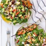 Two plates of harvest salad with shrimp skewers on the side.