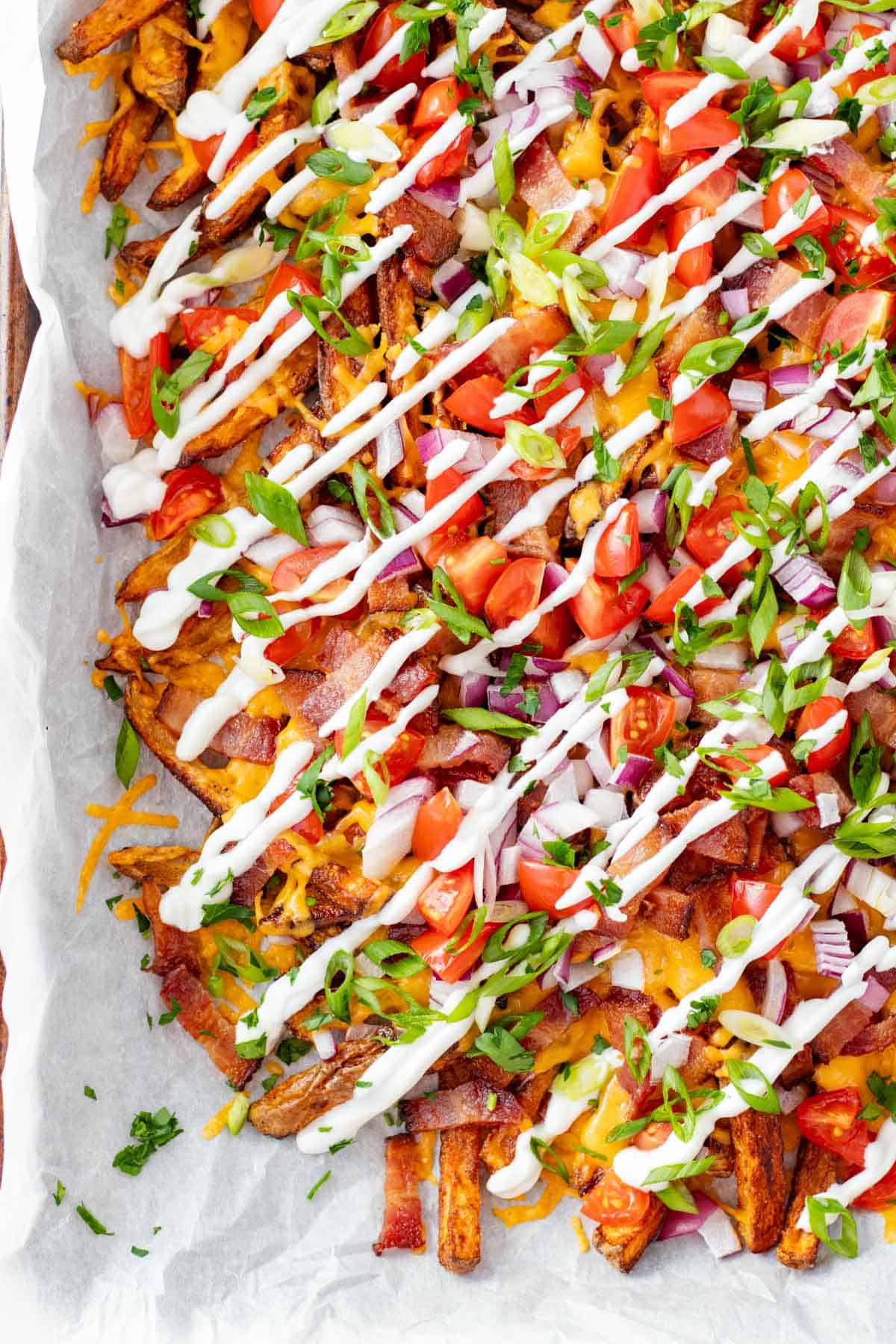 Loaded french fries piled high with topping like tomatoes, red onions, bacon and cheese, finished with a sour cream drizzle.