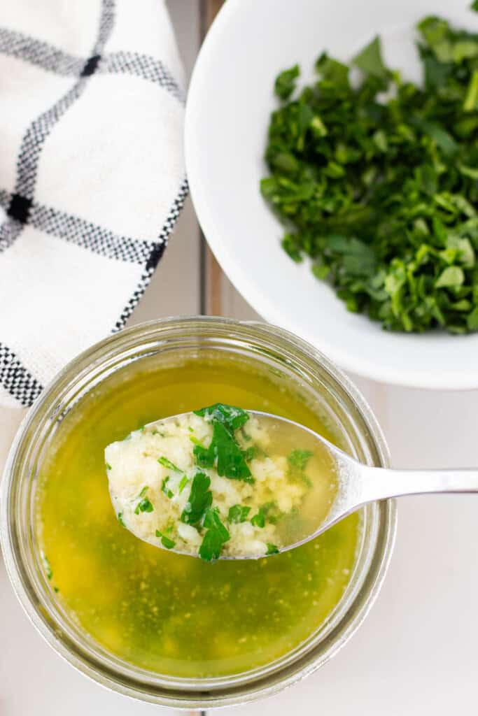 A small mason jar filled with garlic butter with a spoon.