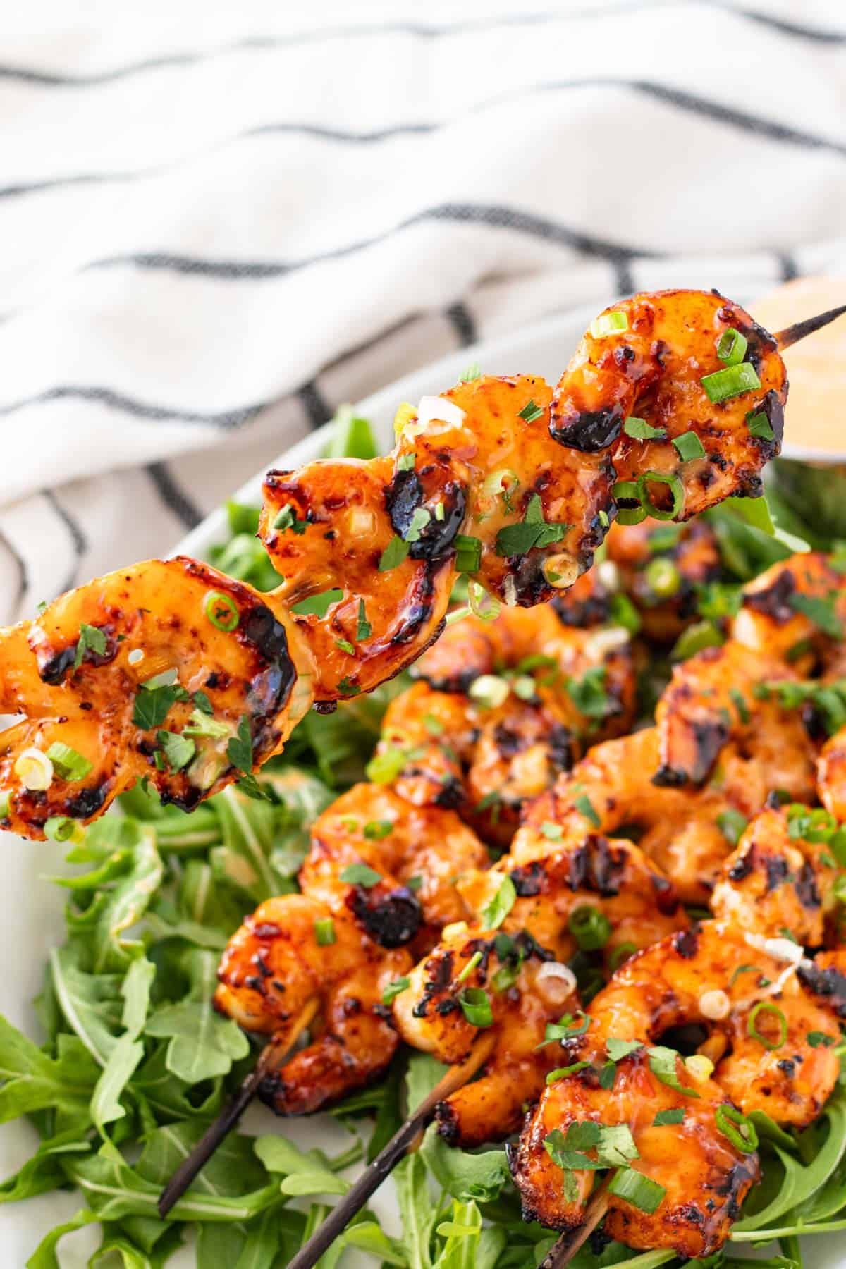 Picking up a grilled shrimp skewer with bang bang sauce, ready to eat.