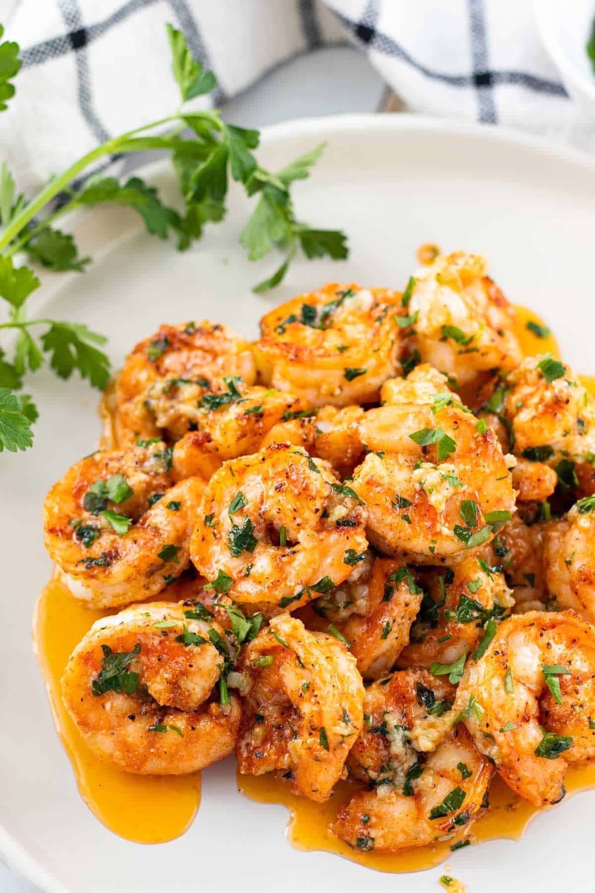 A pile of juicy garlic butter shrimp on a white plate.