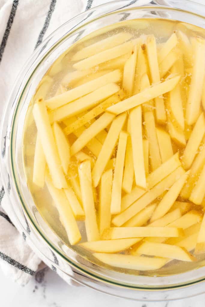 Soaking cut fries in a bowl full of water.