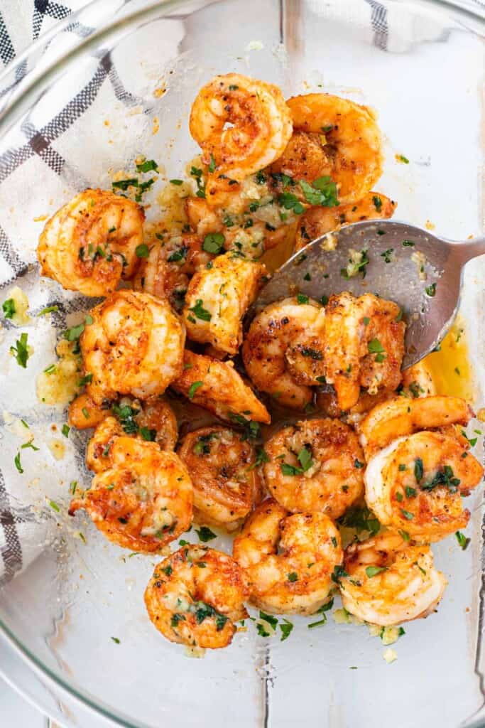 Stirring the shrimp with the garlic butter in a large mixing bowl.
