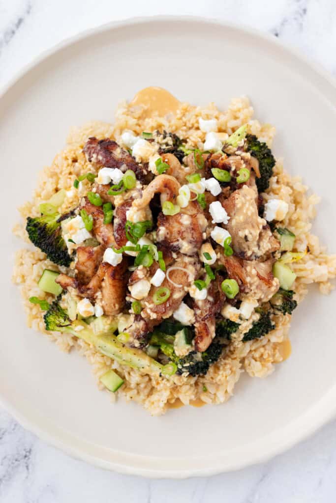 Adding sesame sauce and toppings on top of the rice bowl.