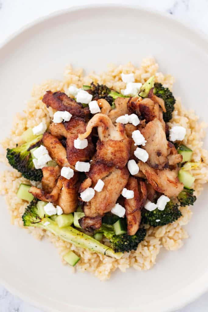 Layering brown rice, broccoli, chicken, and goat cheese onto a plate.