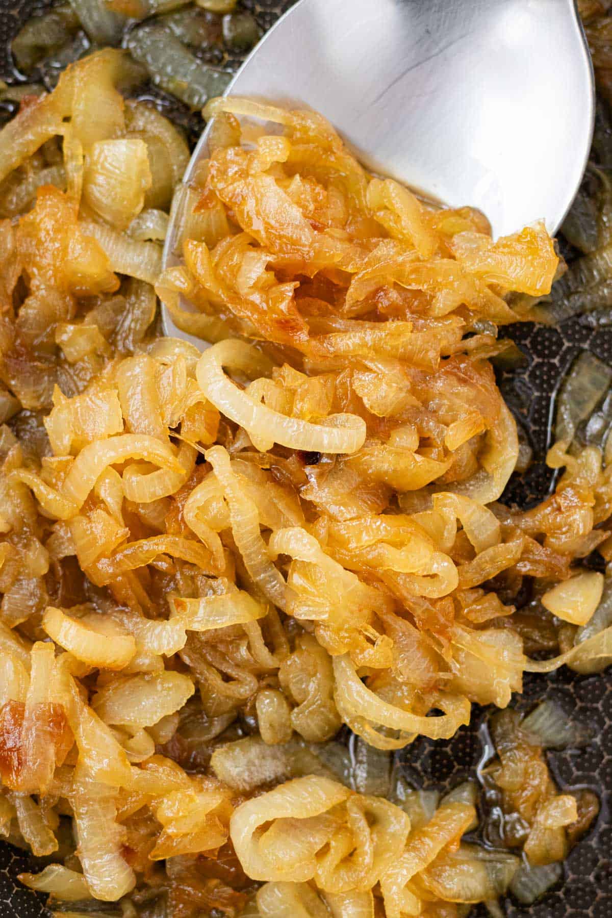 Golden brown caramelized onions in a frying pan.